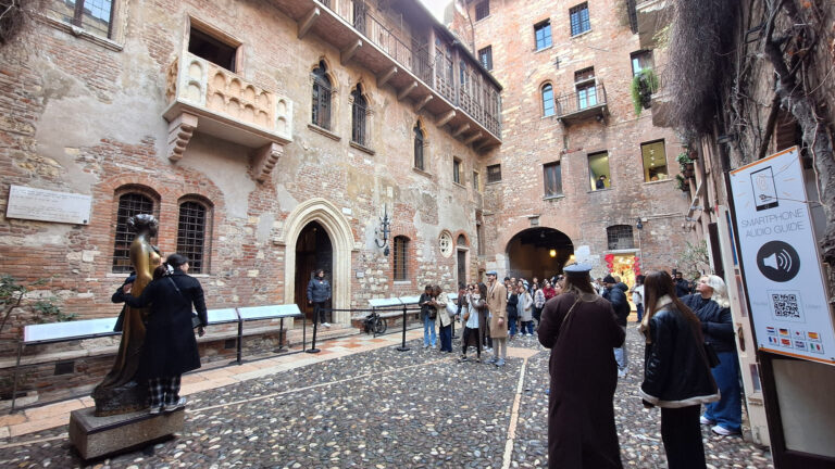 Verona, Italy - November 8, 2024: Cityscape. Juliet's House and Balcony, Juliet sculpture. People in the courtyard.
